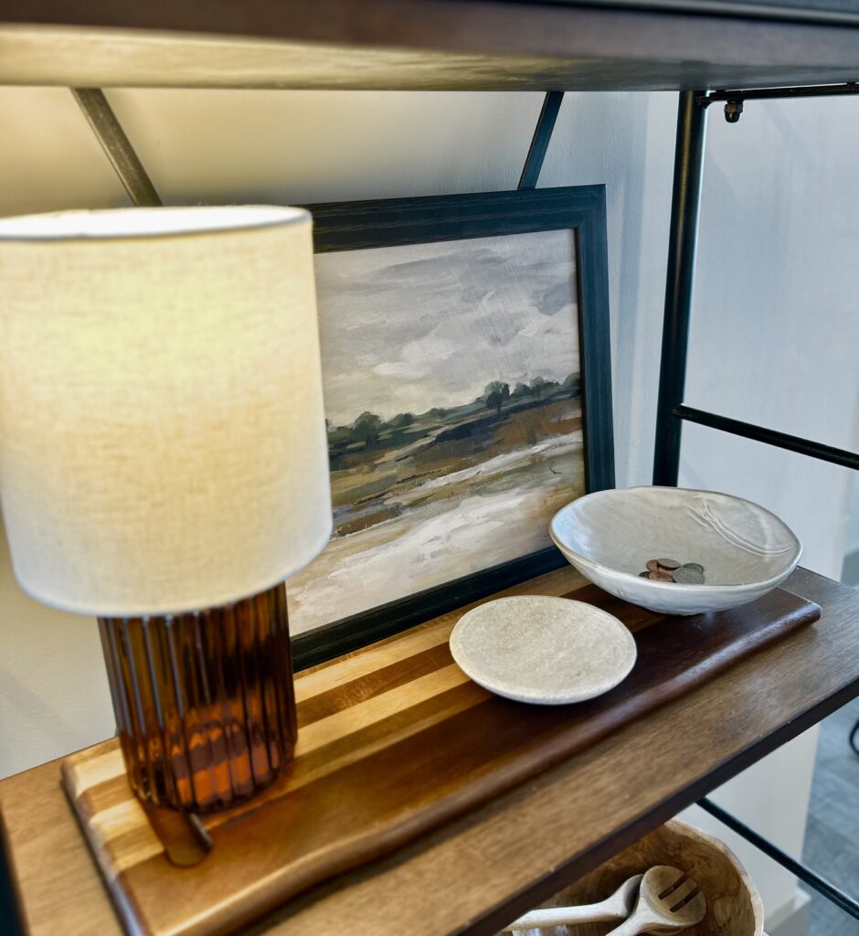 shelf with an amber lamp, artwork, and two ceramic bowls